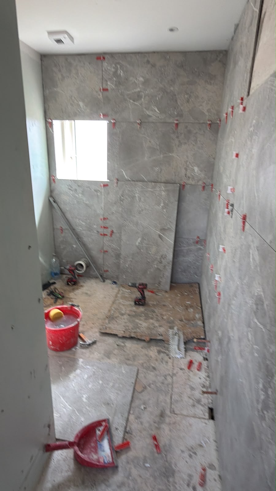 Same bathroom mid-renovation, with tiling in progress and tools on the floor